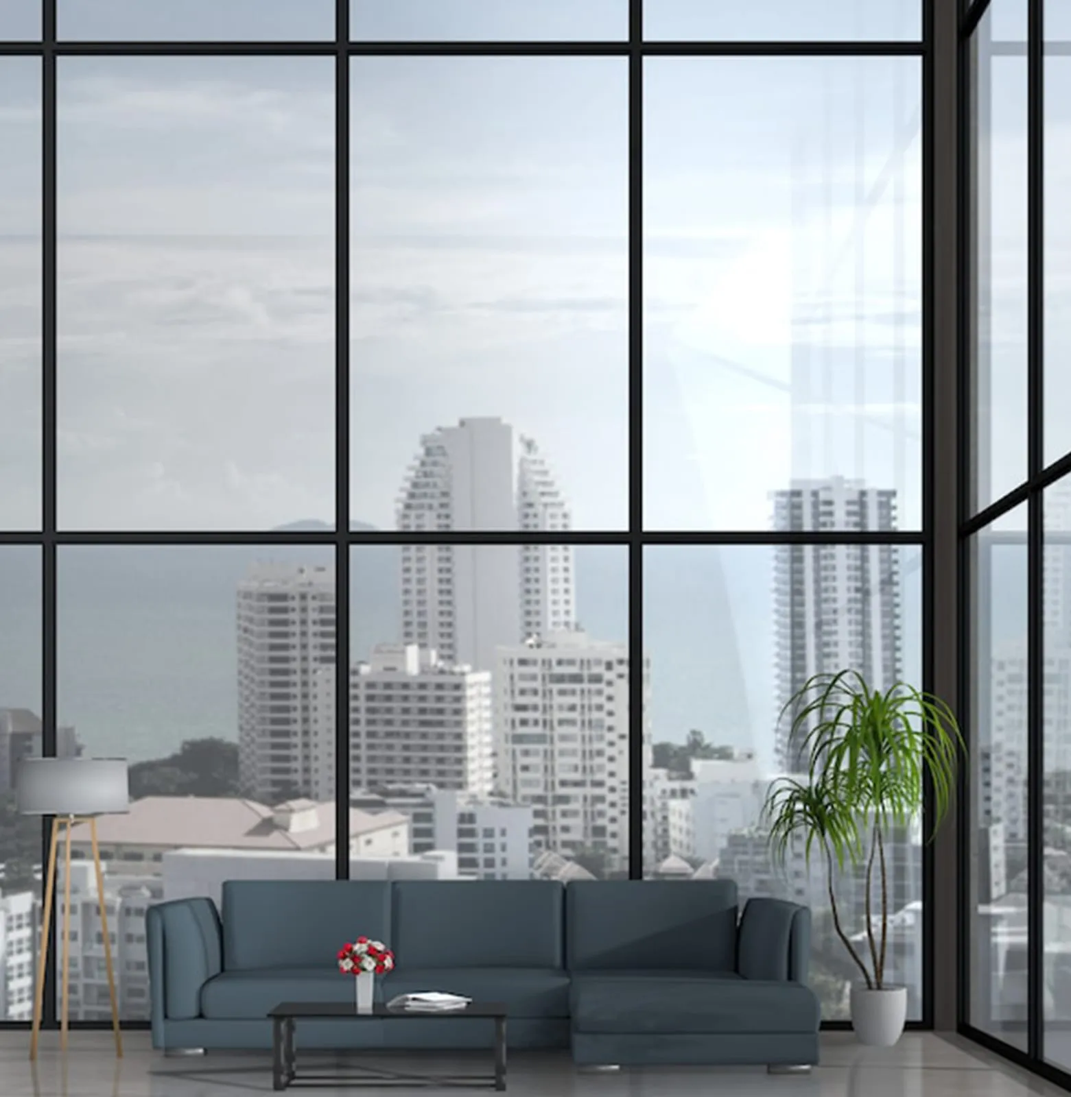 Living room behind full-height dark-framed glazing overlooking a skyline of residential towers
