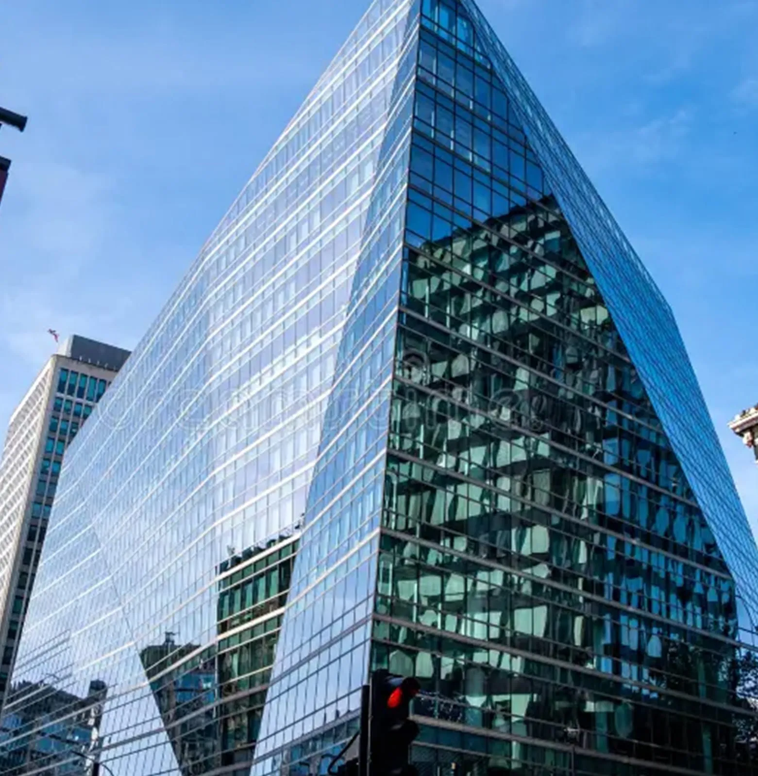 Corner of a dark glazed office block, its reflective panes meeting at a sharp vertical edge