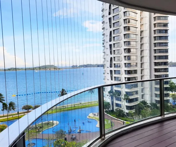 Curved high-floor balcony edged with fine steel cables, swimming pool and sea visible below
