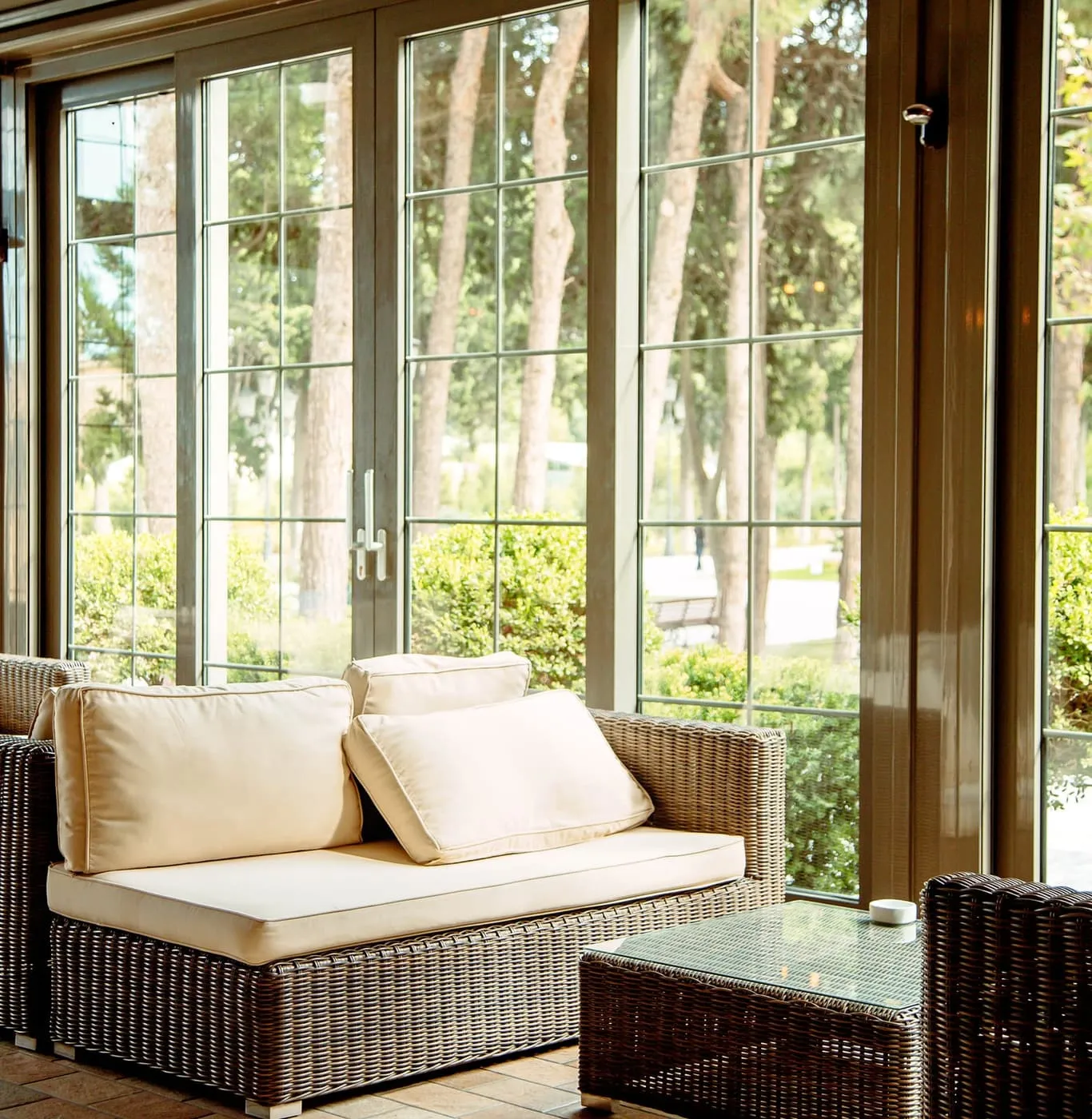 Timber-framed French windows opening from a conservatory seating area onto a wooded garden