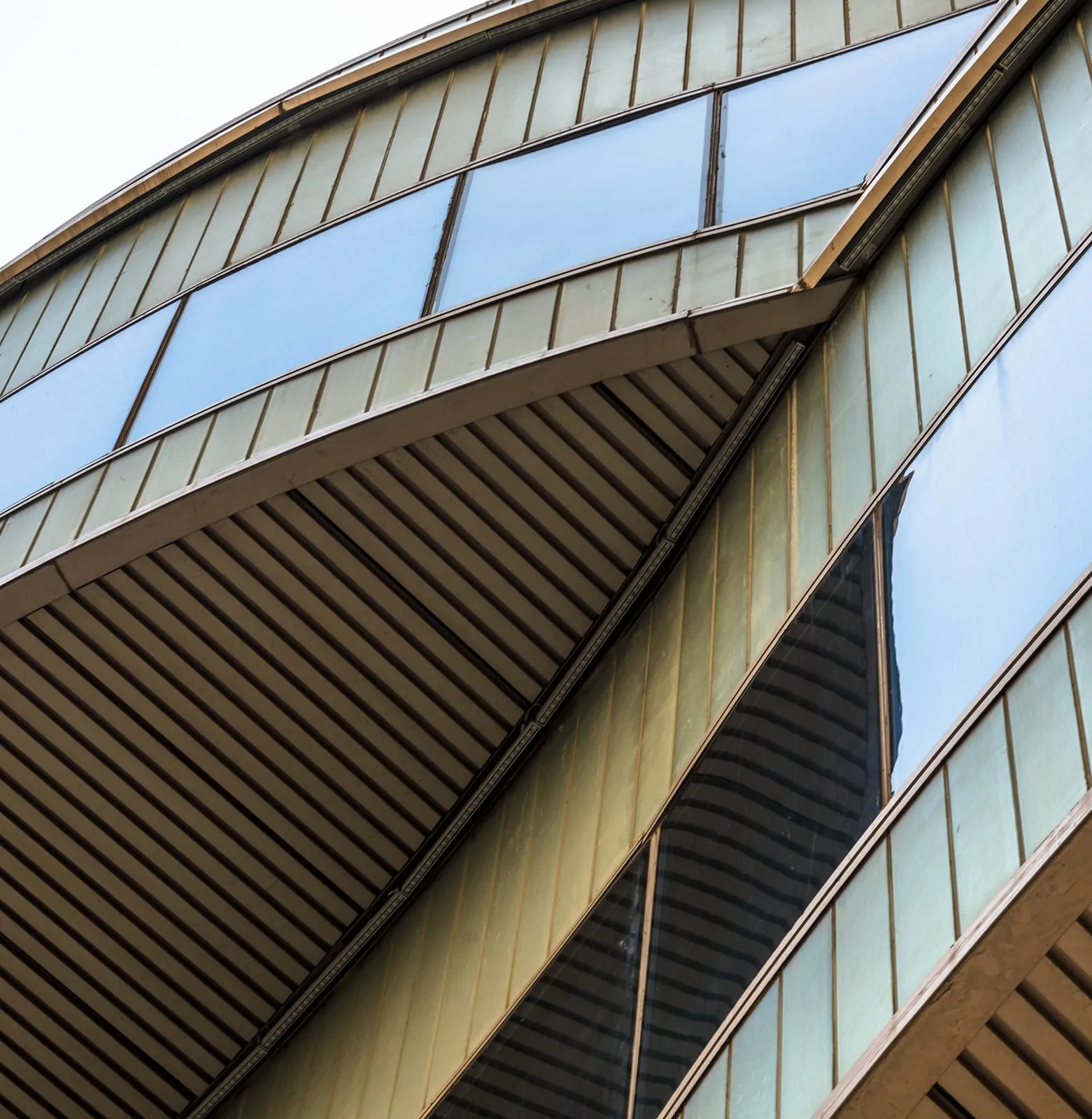 Curved bronze composite panel façade with glazing bands following the building's sweep
