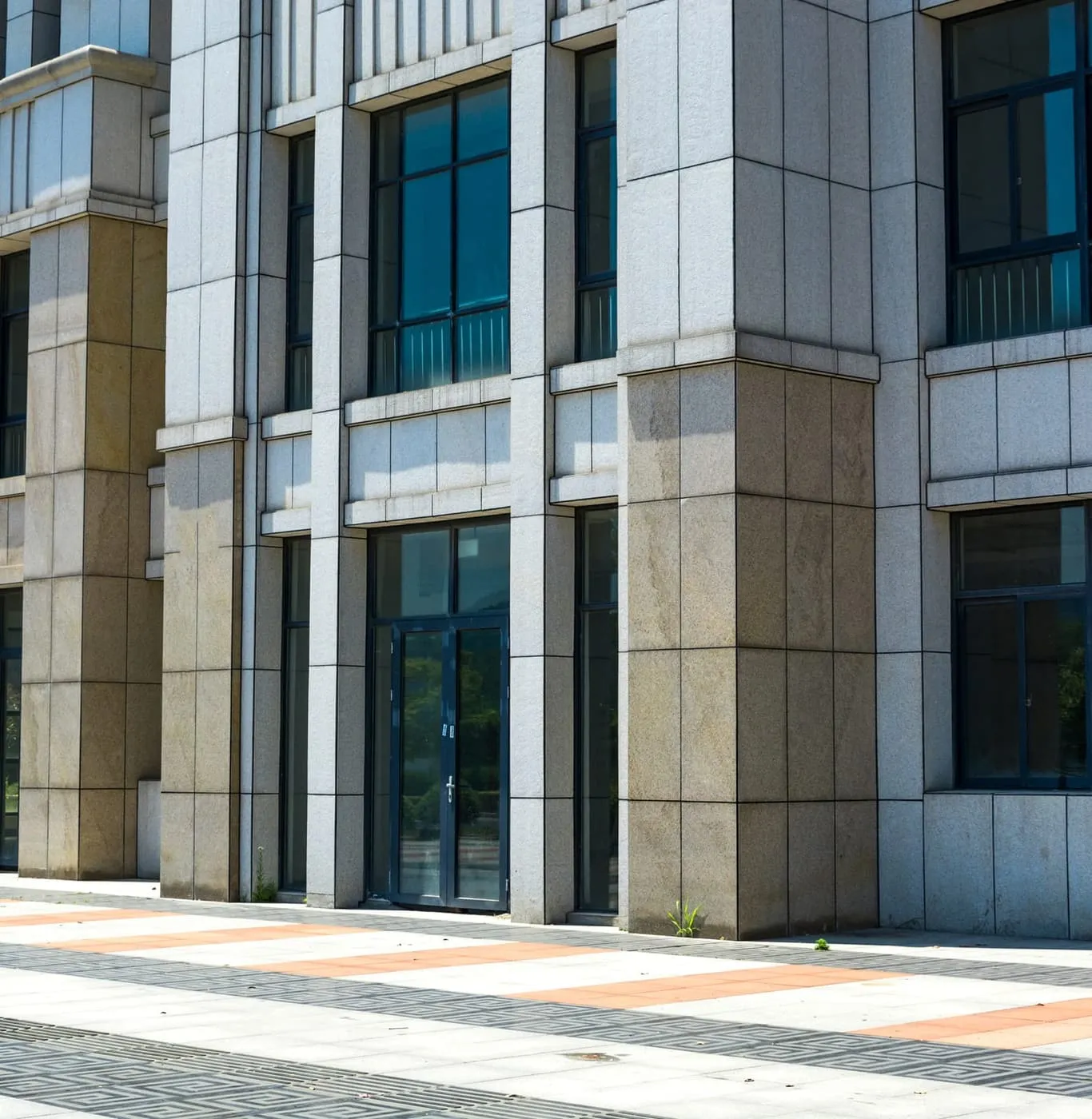 Contemporary low-rise office block clad in grey panels and full-height glazing under a clear sky