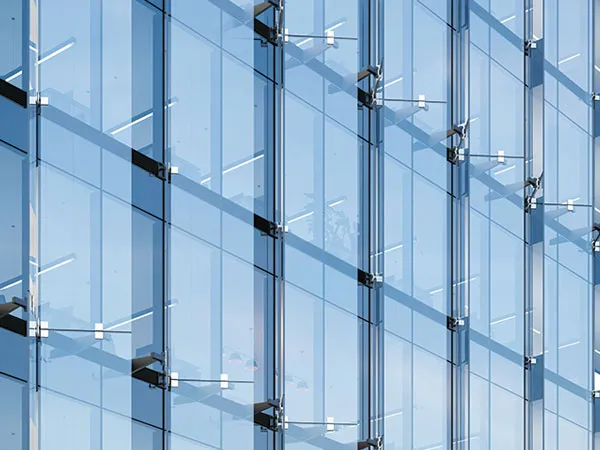 Blue glass curtain wall held by spider fittings, the bolted arms visible across each pane