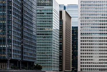 Cluster of glass-clad high-rise office towers seen from street level against a pale sky