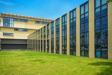 Long low institutional building with continuous ribbon glazing, lawn running along its front