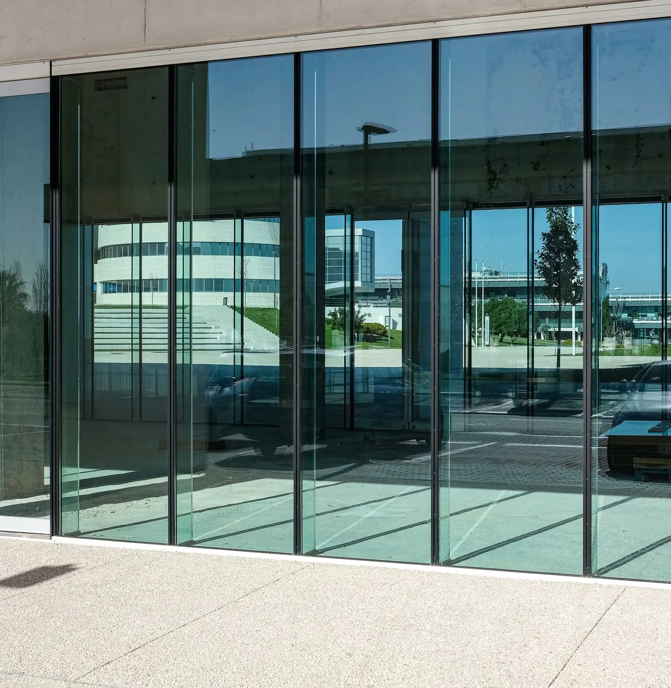 Glazed commercial entrance screen with slim dark framing reflecting the street outside