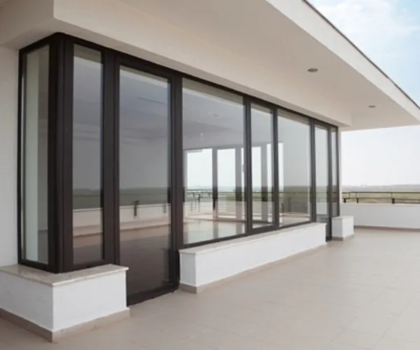 Dark-framed full-height sliding glazing running along a terrace, open landscape beyond