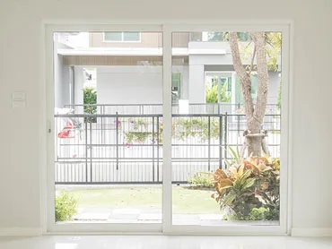 White uPVC sliding patio door standing open onto a planted garden and paved path