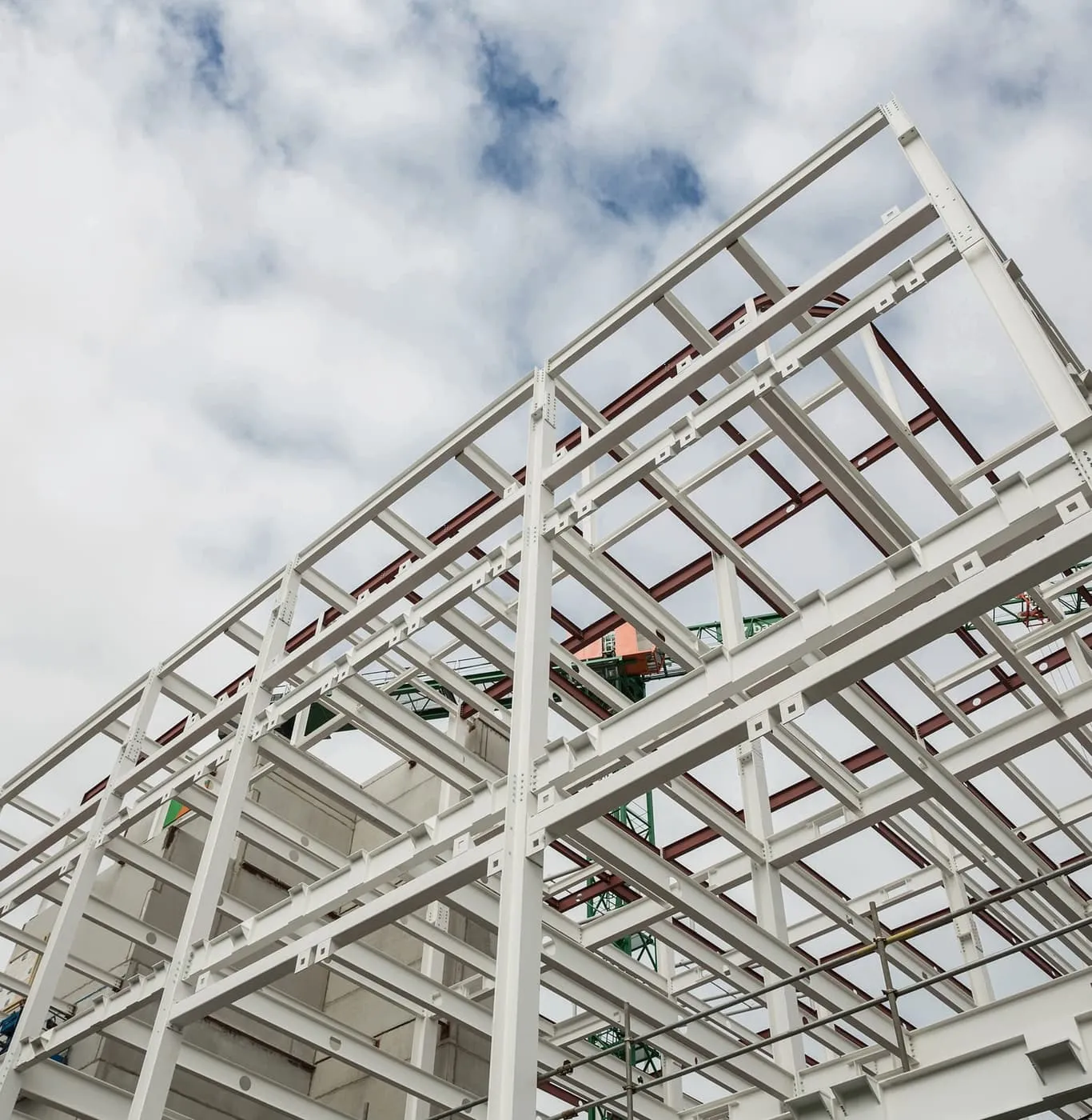 White steel portal frame roof structure under construction, purlins running between frames