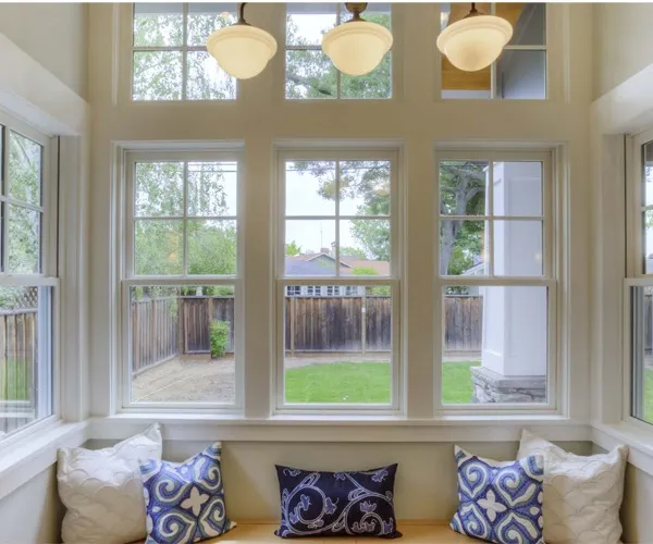 Bay of white-painted sash windows above a cushioned window seat, garden visible outside
