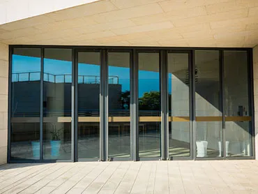 Dark slim-framed sliding glass doors opening from a living room onto a paved terrace