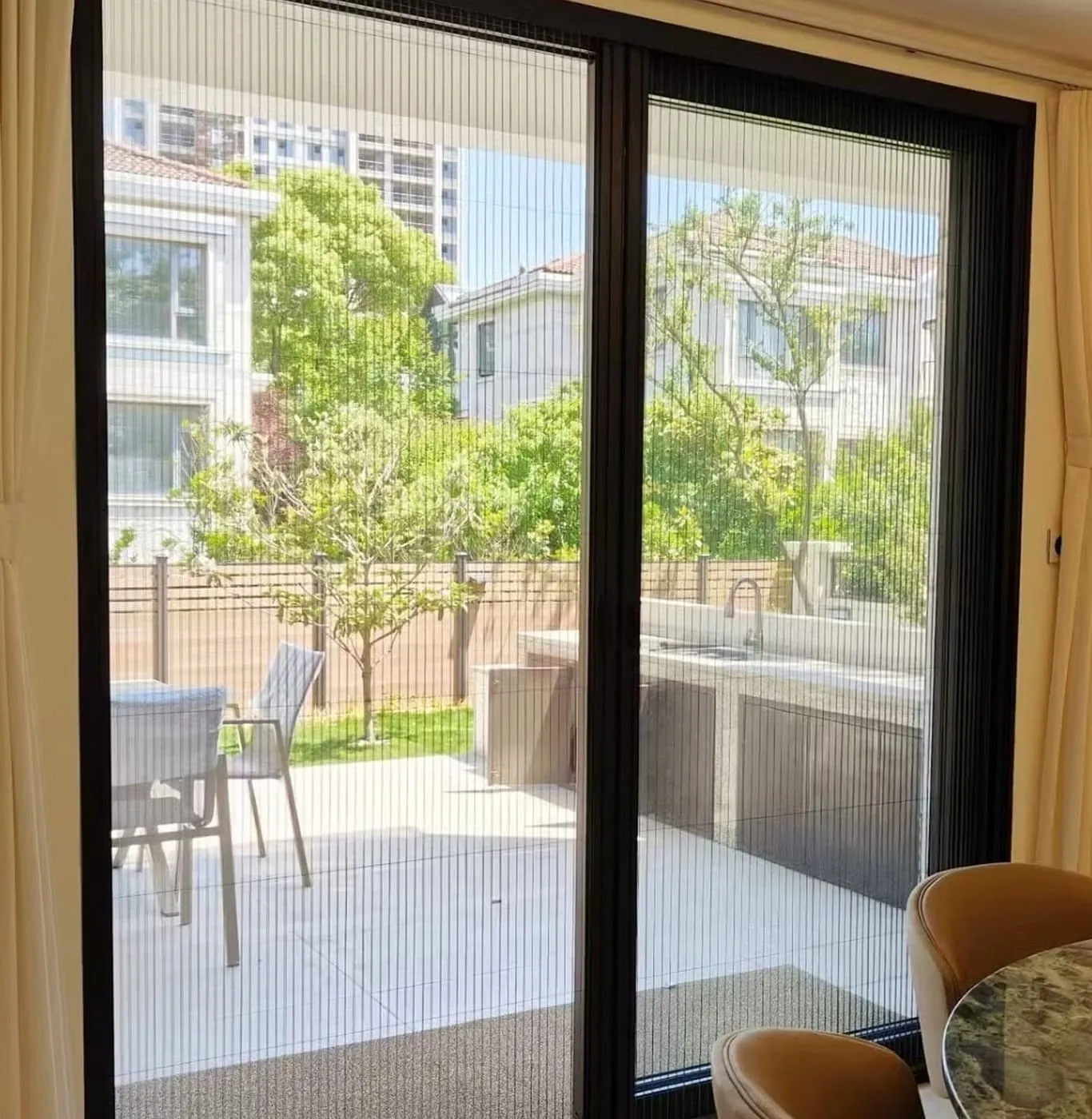 Sliding patio door fitted with a fine mesh screen panel, terrace furniture visible through it