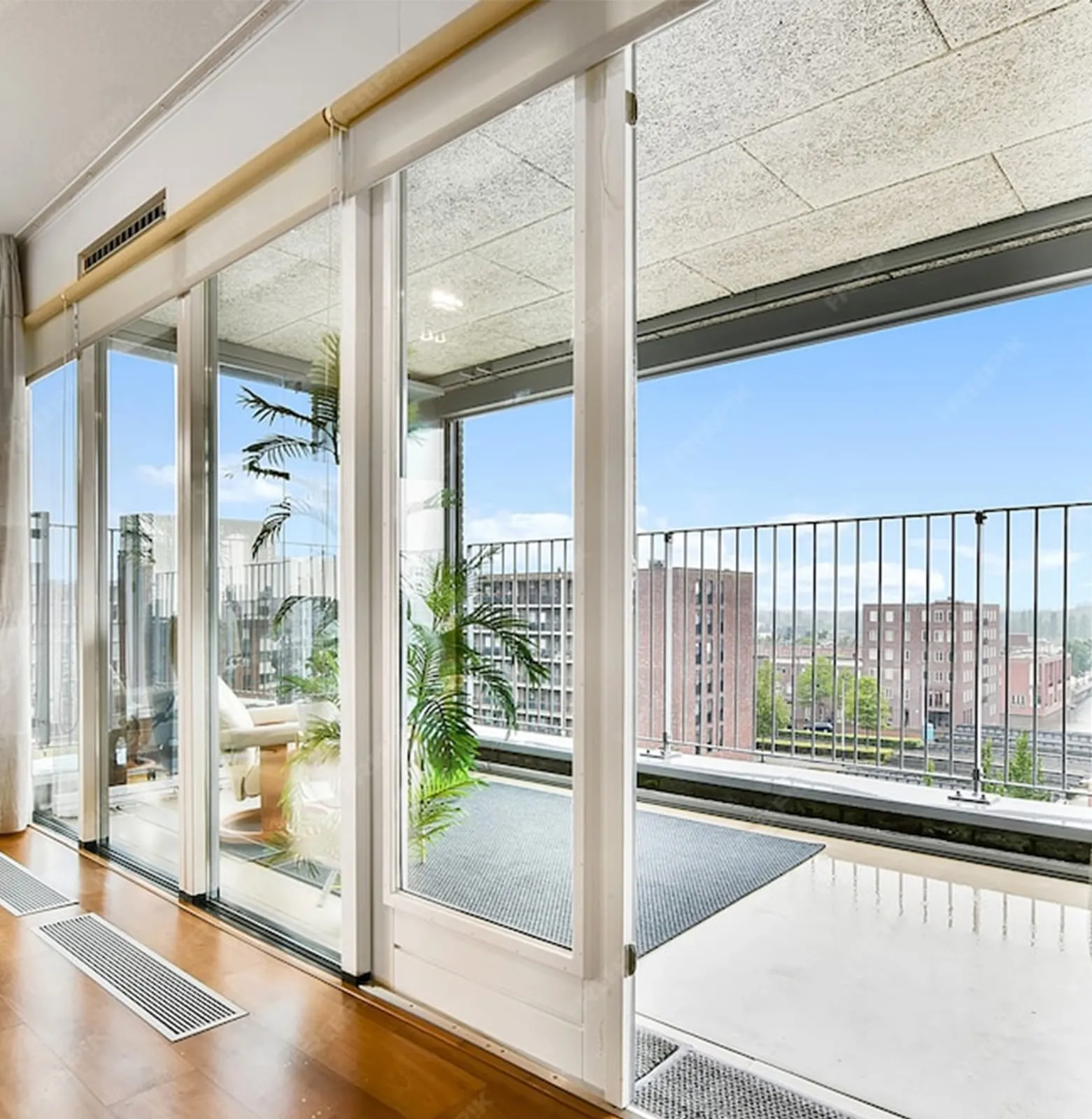 Wide sliding glass panels opening from a room onto a balcony with a city view beyond