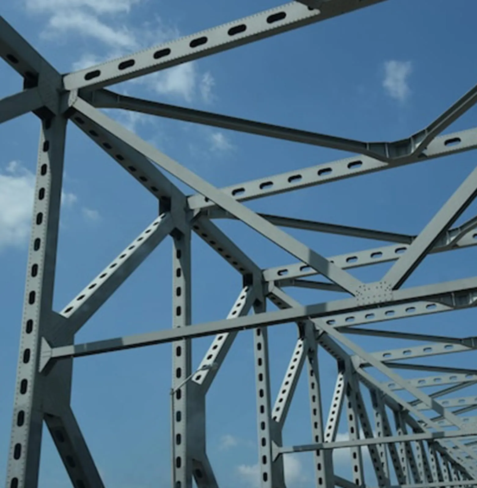 Detail of a steel truss joint with bolted gusset plates against a clear blue sky