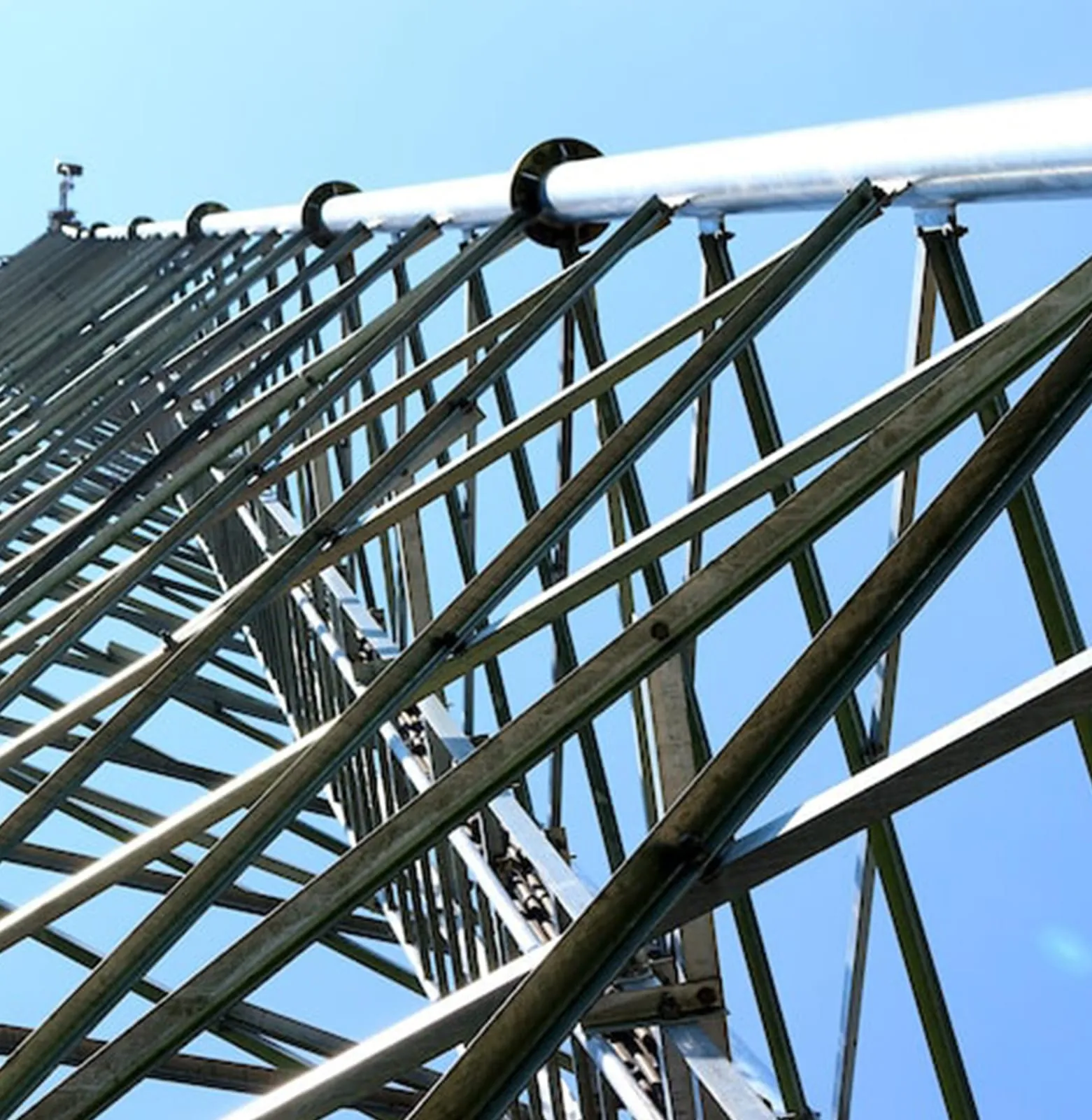 Curved tubular steel roof frame seen from below, members converging overhead