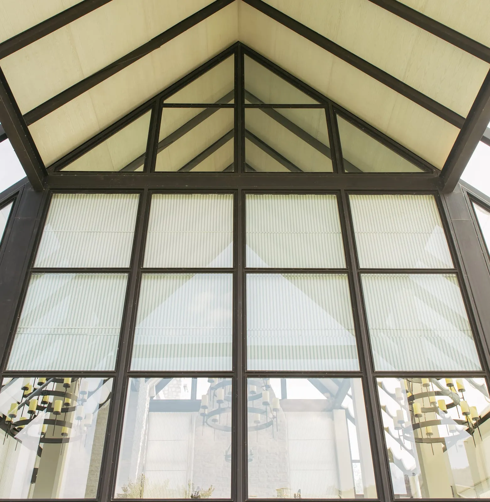 Gabled steel and polycarbonate canopy structure seen from inside, frame members exposed