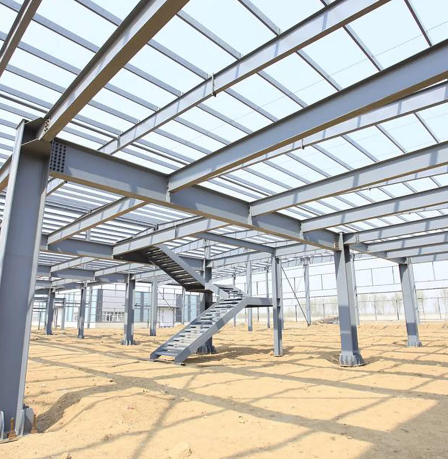 Steel portal frame warehouse under construction with an access staircase in the foreground