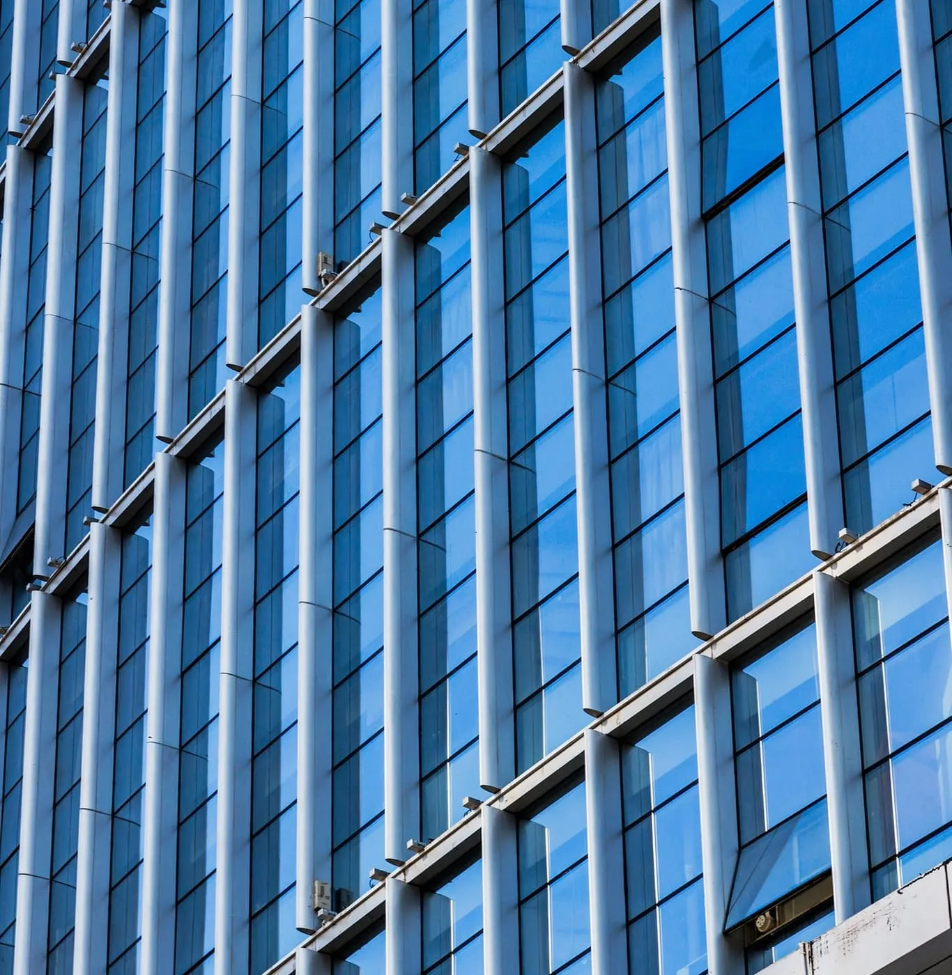 Blue glass curtain wall rising against the sky with slim vertical structural fins