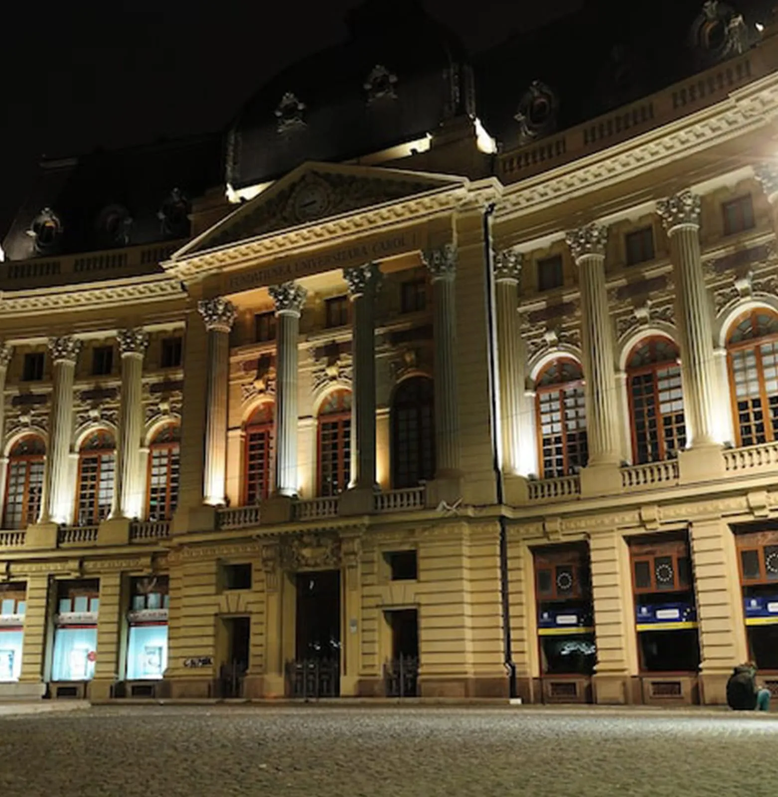 Art-deco theatre frontage at night, decorative parapet and tall windows picked out by uplighting