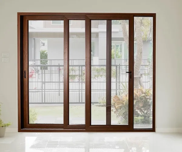 Wood-effect uPVC sliding patio door set in a white wall, garden and boundary railing beyond